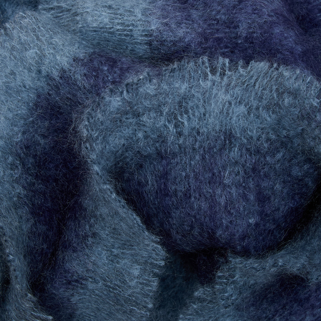 A close-up of soft, fuzzy fabric or yarn in a mottled blend of slate blue, navy, and charcoal gray.